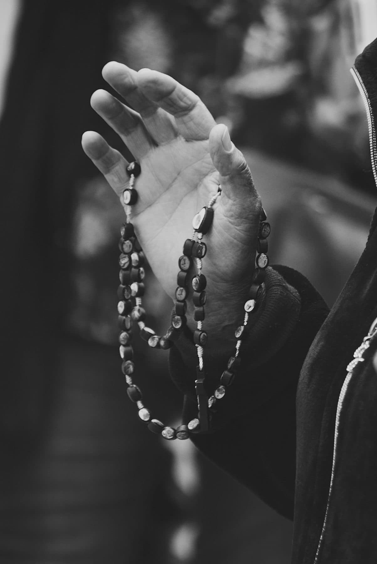 Hands holding a rosary, in black and white