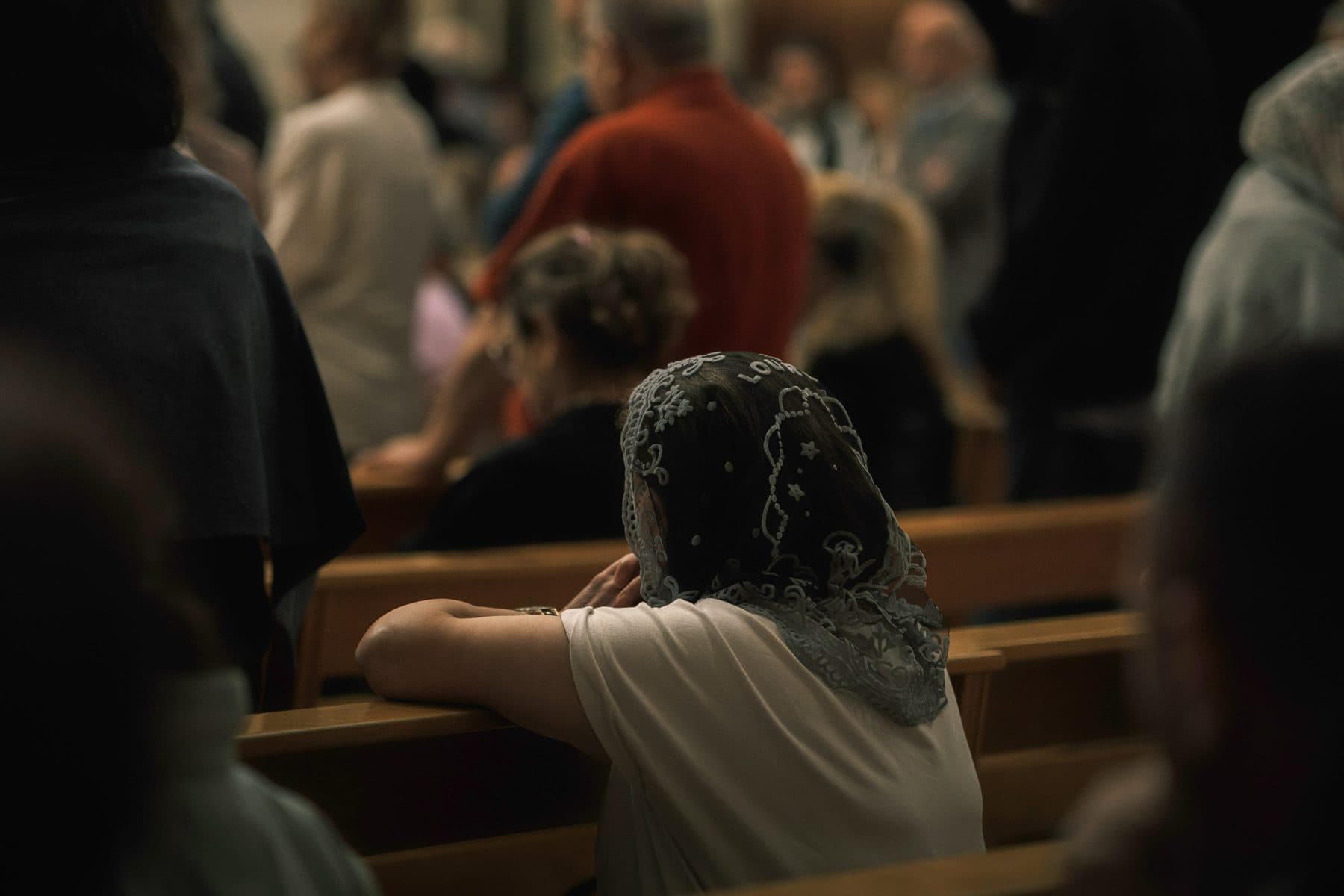 A woman praying alone in a church pew