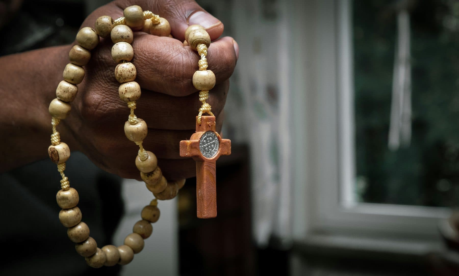 A wooden rosary held in a hand