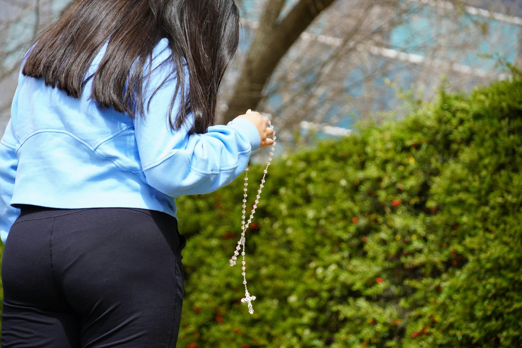 A woman walking with a rosary in her hand
