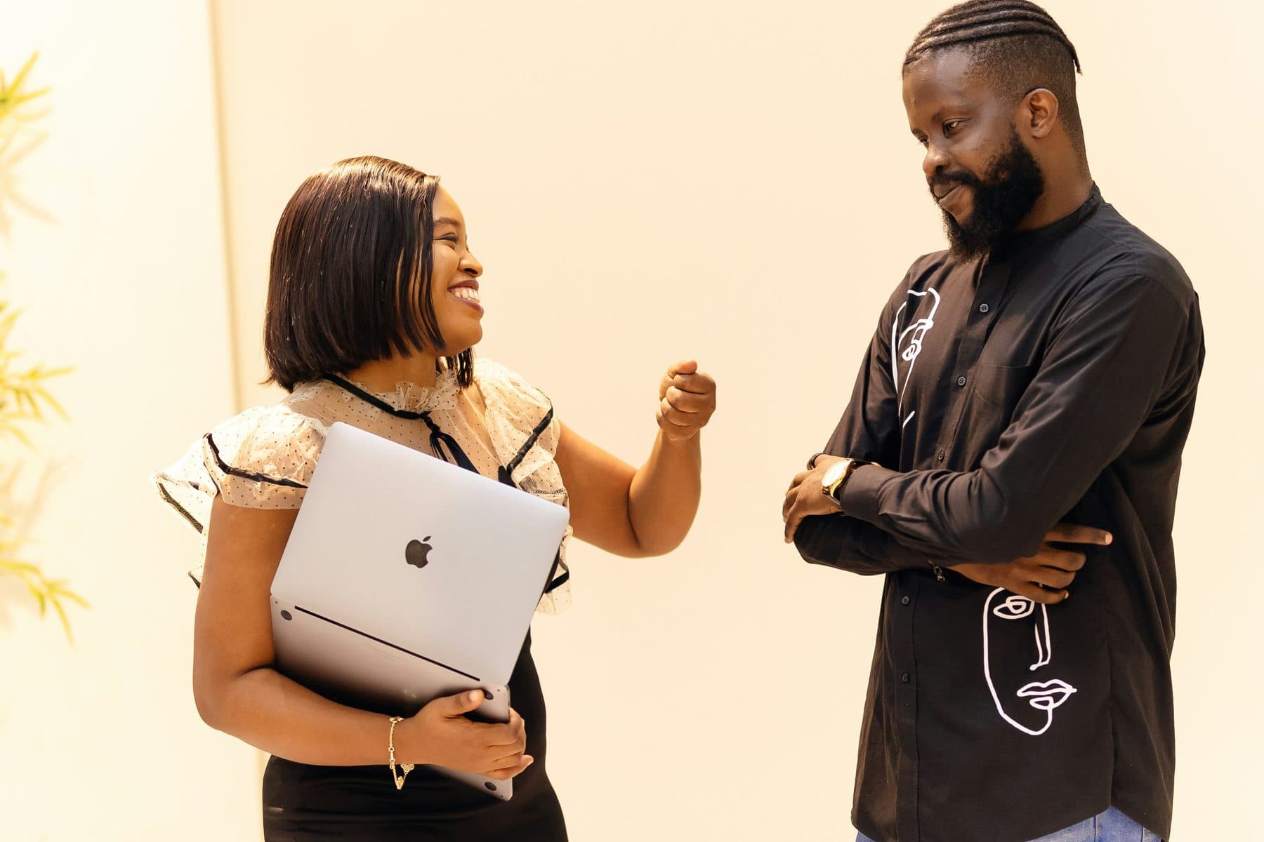 Two colleagues talking, one holding a laptop